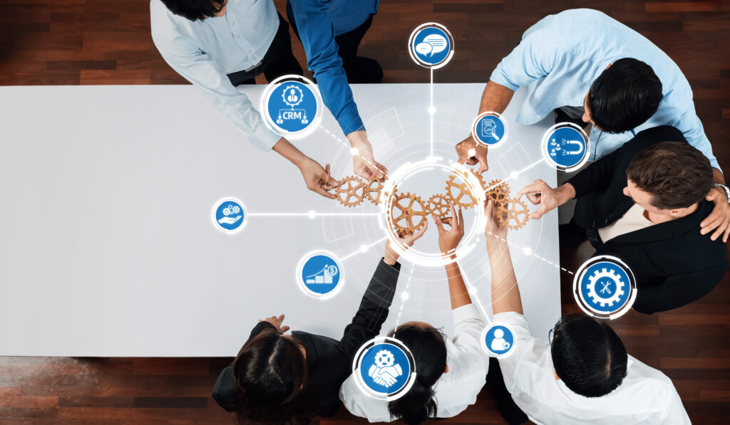 A diverse team collaborating around a table with a digital overlay of interlocking gears and icons for CRM, lead magnets, and sales automation.