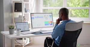 Professional analyzing a B2B marketing analytics dashboard with charts and line graphs on a desktop monitor in a modern office.